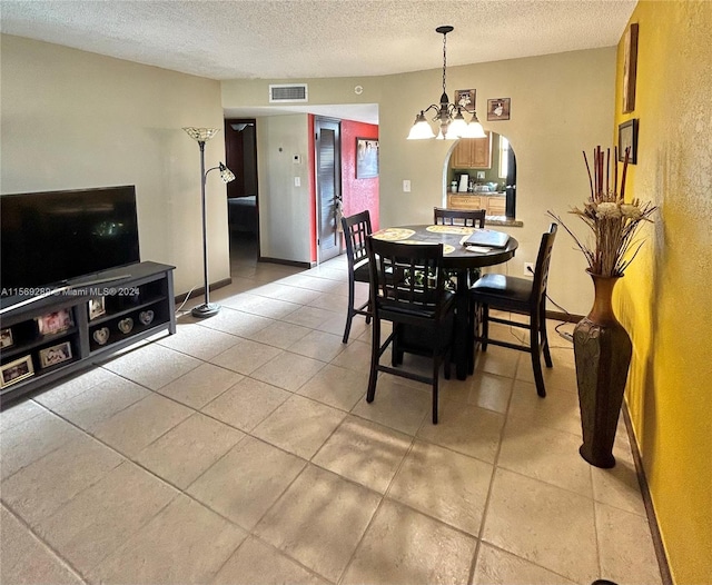 dining space featuring an inviting chandelier, a textured ceiling, and light tile flooring