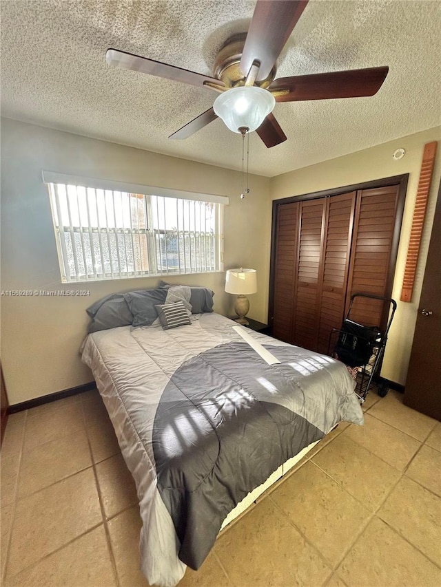 tiled bedroom with a closet, ceiling fan, a textured ceiling, and multiple windows