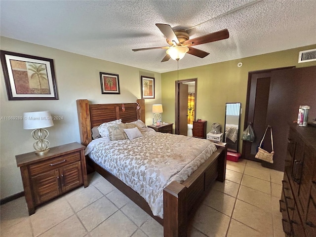 bedroom featuring ceiling fan, light tile flooring, and a textured ceiling