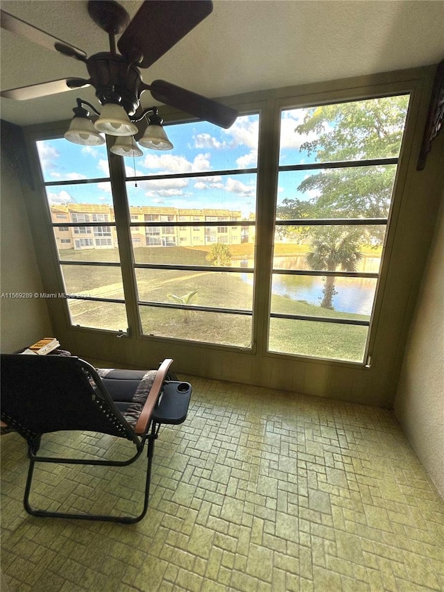 sunroom with a water view and ceiling fan