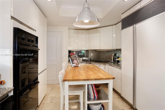 kitchen with white cabinets, paneled fridge, backsplash, pendant lighting, and a raised ceiling