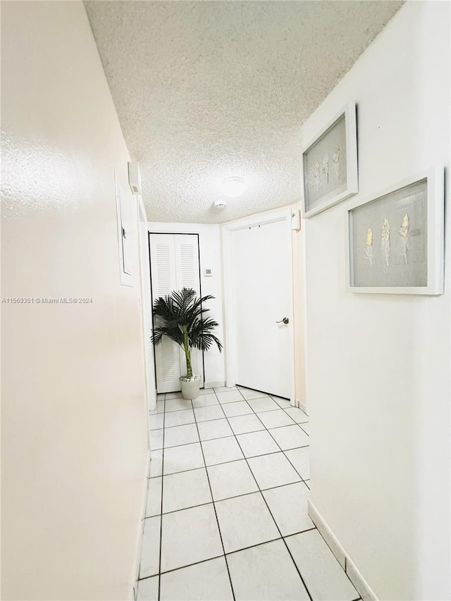 hallway with light tile patterned floors and a textured ceiling