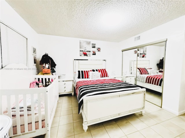 bedroom featuring light tile patterned floors, a textured ceiling, and a closet