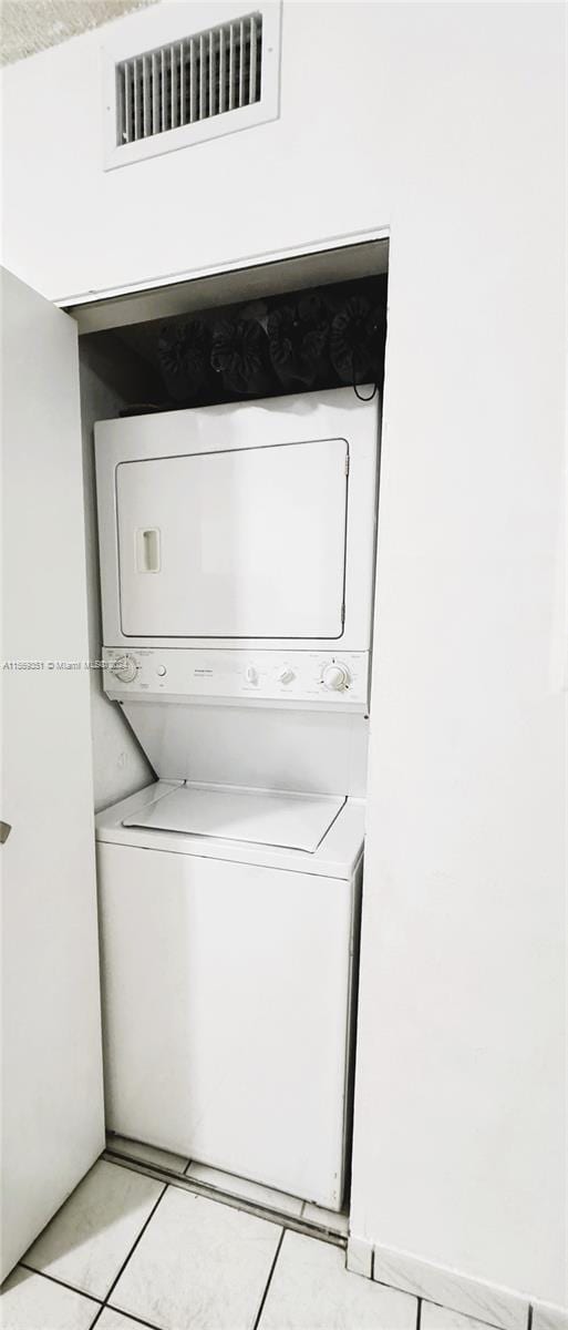 laundry room featuring stacked washer / dryer and light tile patterned floors