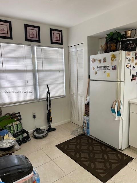 kitchen with light tile flooring and white fridge