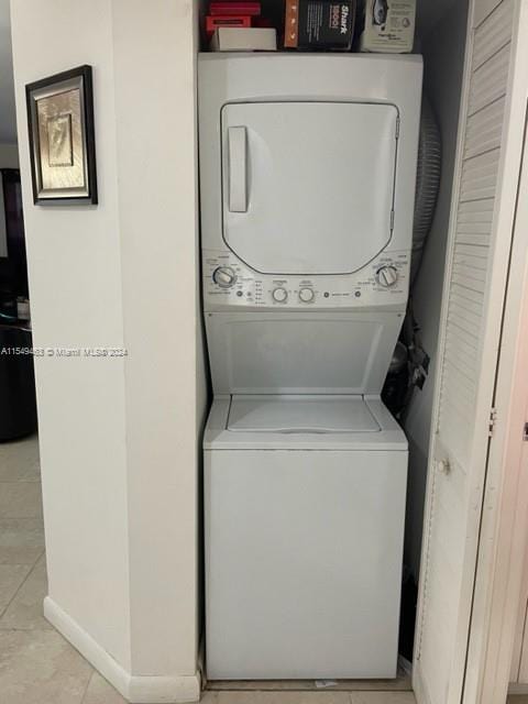 laundry area with stacked washer and clothes dryer and light tile flooring