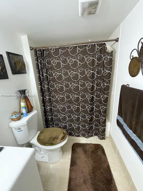 bathroom featuring tile floors, toilet, and shower / bath combo with shower curtain