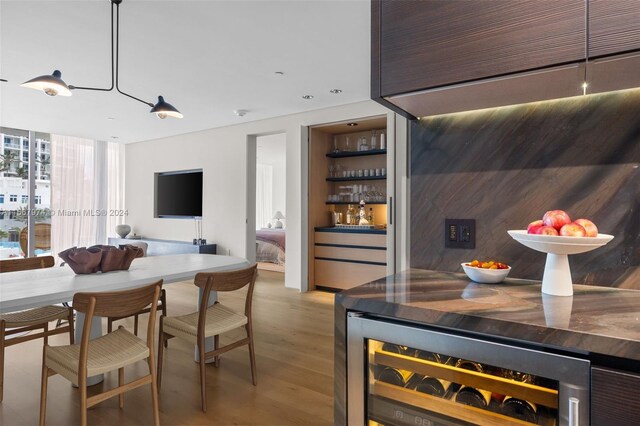 interior space featuring beverage cooler, light hardwood / wood-style flooring, and bar