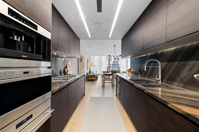 kitchen with appliances with stainless steel finishes, light hardwood / wood-style floors, tasteful backsplash, and sink