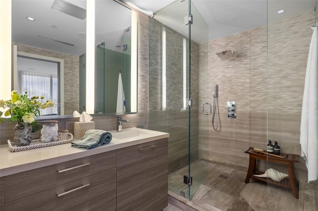 bathroom with a shower with door and vanity