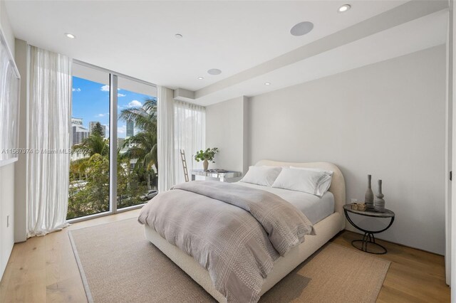 bedroom with multiple windows, light hardwood / wood-style flooring, and a wall of windows