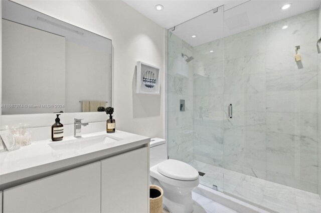 bathroom featuring a shower with door, vanity, and toilet