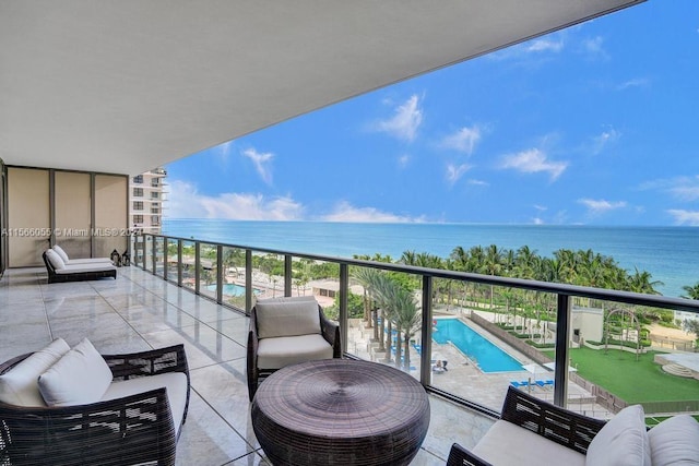 balcony with a water view, outdoor lounge area, and a community pool