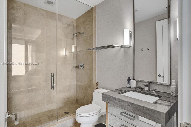 bathroom featuring a shower with door, toilet, and oversized vanity