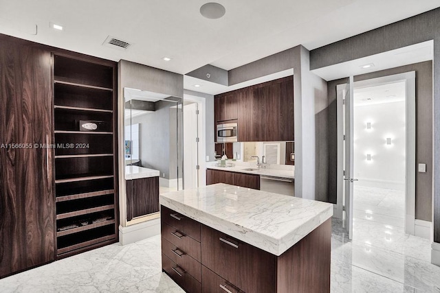 kitchen featuring appliances with stainless steel finishes, dark brown cabinets, sink, light tile floors, and a kitchen island