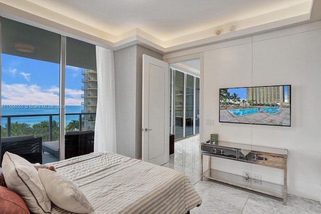 tiled bedroom featuring a water view, a tray ceiling, and access to outside