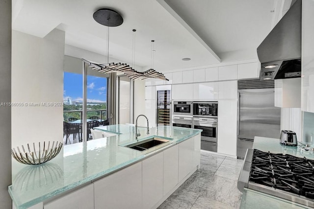 kitchen with light tile floors, sink, white cabinetry, decorative light fixtures, and light stone countertops