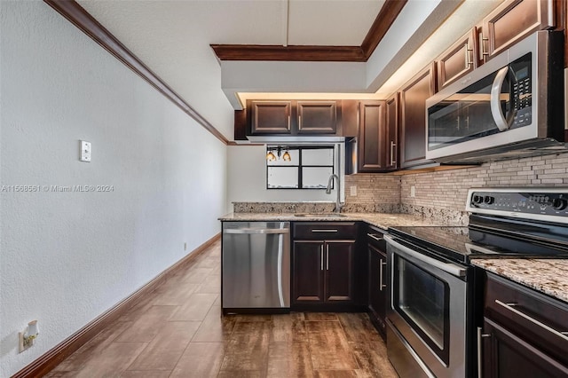 kitchen featuring light stone countertops, sink, stainless steel appliances, backsplash, and ornamental molding