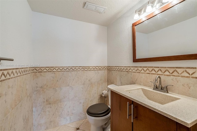 bathroom featuring tile patterned floors, tile walls, vanity, and a textured ceiling