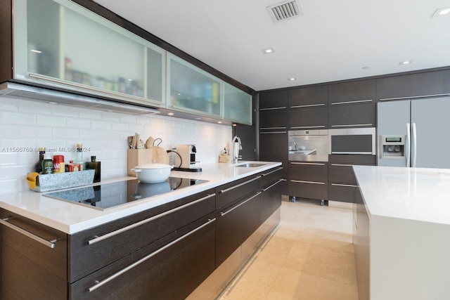 kitchen with a center island, sink, tasteful backsplash, light tile flooring, and stainless steel appliances