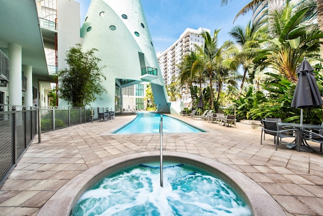 view of swimming pool featuring a patio and a hot tub