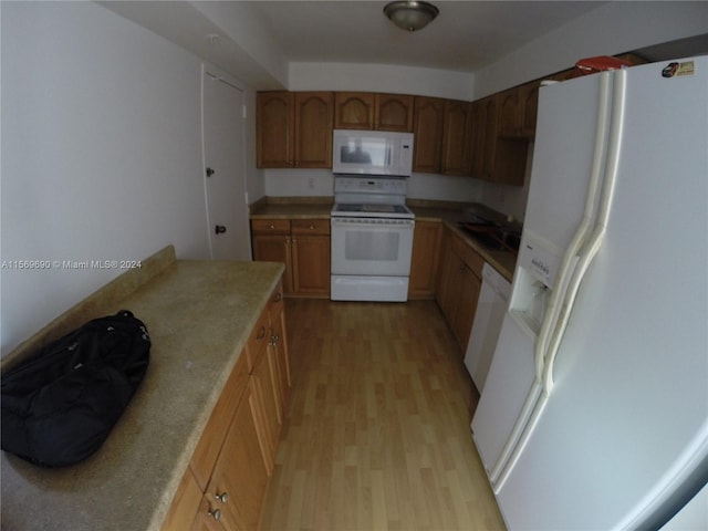 kitchen with light hardwood / wood-style flooring, white appliances, and sink