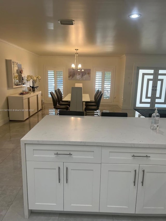 kitchen with white cabinets, light stone countertops, light tile floors, and decorative light fixtures