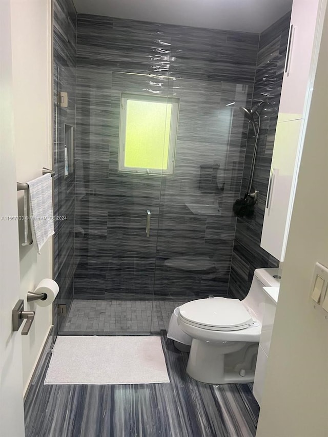 bathroom featuring a shower with shower door and toilet