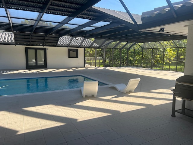 view of swimming pool featuring glass enclosure and a patio