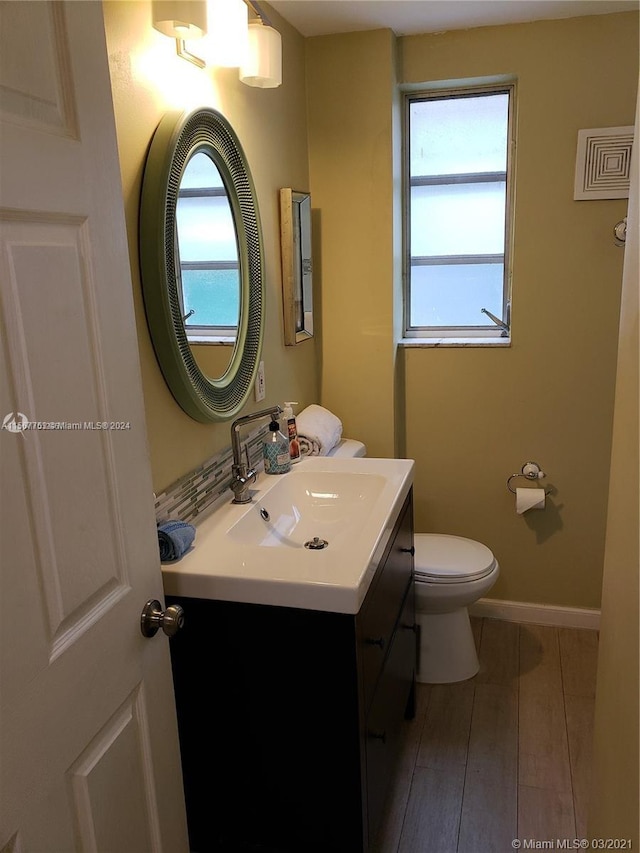 bathroom with hardwood / wood-style floors, plenty of natural light, large vanity, and toilet