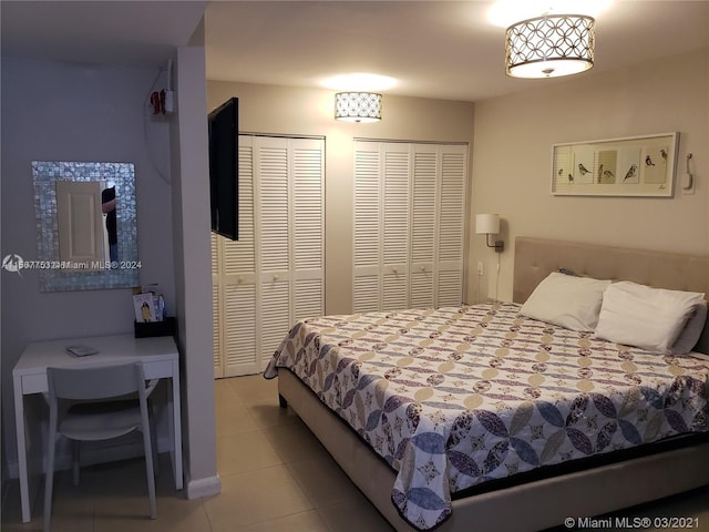 bedroom featuring light tile floors and multiple closets