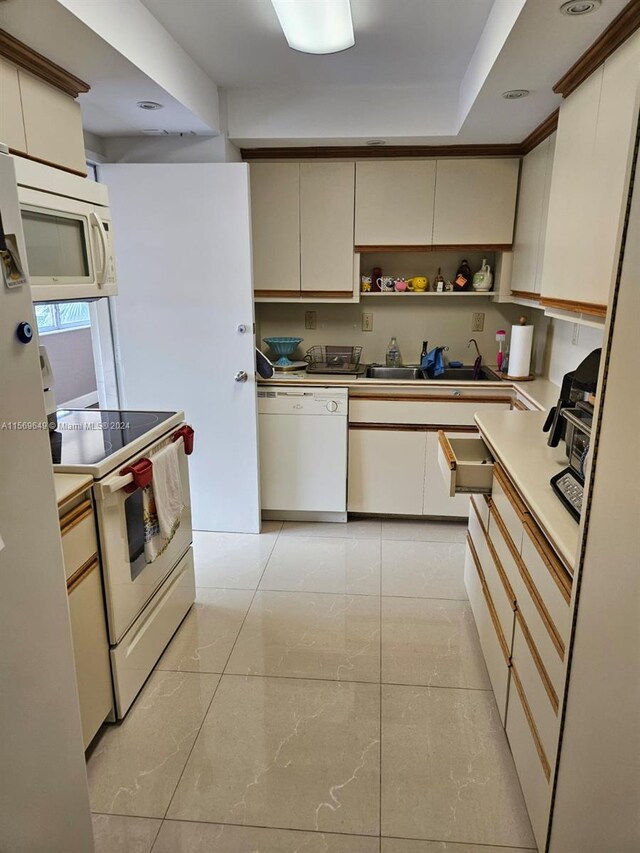 kitchen with sink, white appliances, and light tile patterned flooring