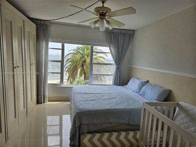 tiled bedroom featuring ceiling fan, a closet, and wooden walls