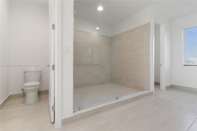 bathroom with tile patterned floors, toilet, and tiled shower