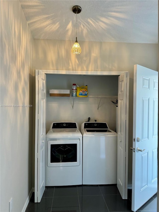 laundry room featuring washer and clothes dryer and dark tile flooring