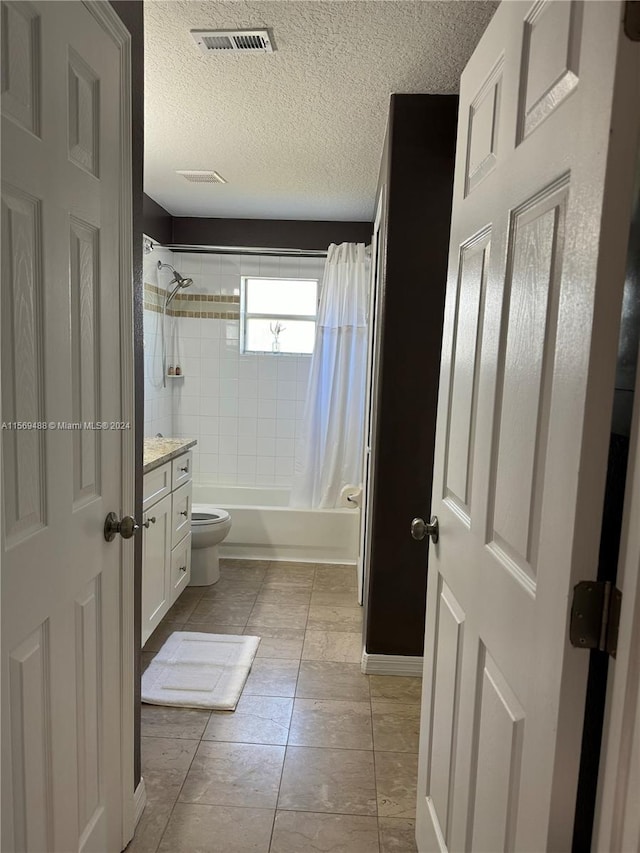 full bathroom featuring shower / bath combo, vanity, tile flooring, toilet, and a textured ceiling