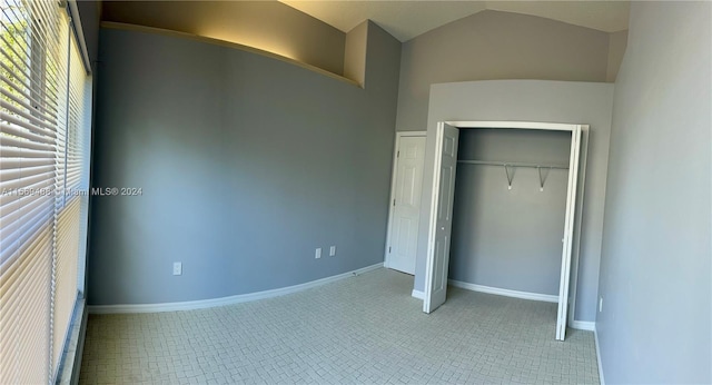 unfurnished bedroom with a closet, lofted ceiling, and light tile floors