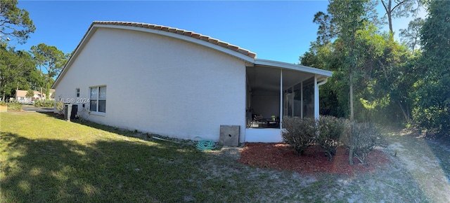 view of property exterior featuring a yard, a sunroom, and central AC unit