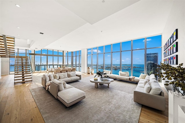 living room with floor to ceiling windows, light hardwood / wood-style flooring, and a water view