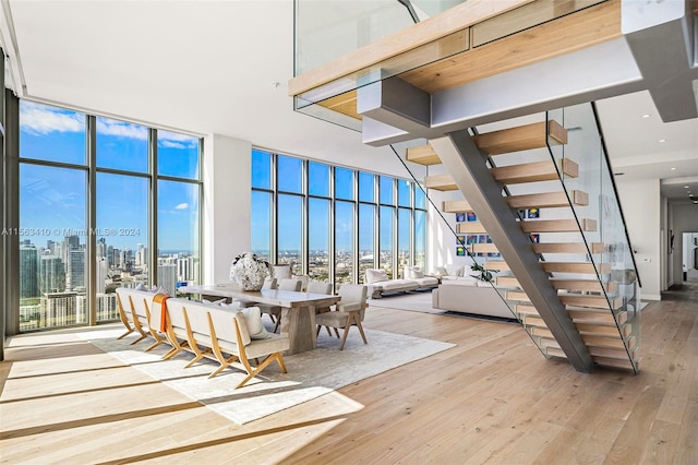 staircase with a towering ceiling, light hardwood / wood-style floors, and expansive windows