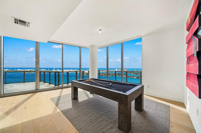 recreation room featuring a water view, a wealth of natural light, pool table, and light wood-type flooring