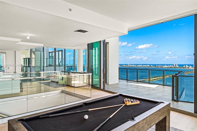 recreation room featuring a water view, light hardwood / wood-style flooring, pool table, and expansive windows