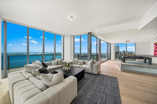 living room featuring a water view, light hardwood / wood-style flooring, expansive windows, and plenty of natural light