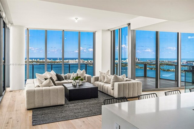 living room featuring light hardwood / wood-style flooring, a water view, and a wall of windows