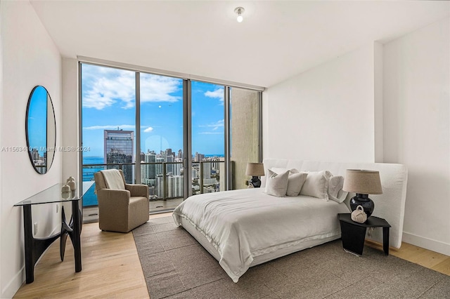 bedroom with light hardwood / wood-style floors, expansive windows, and a water view