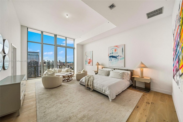 bedroom featuring a wall of windows, light wood-type flooring, and access to exterior