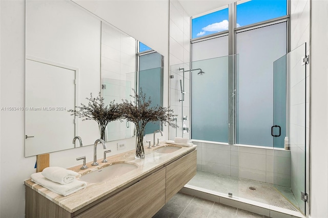 bathroom with walk in shower, vanity with extensive cabinet space, double sink, and tile flooring