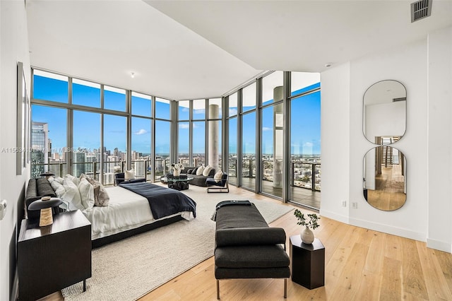 bedroom with light hardwood / wood-style flooring, expansive windows, and multiple windows