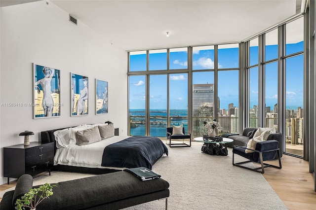 bedroom with a wall of windows, a water view, and light wood-type flooring