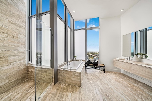 bathroom featuring hardwood / wood-style floors, shower with separate bathtub, vanity with extensive cabinet space, and a towering ceiling